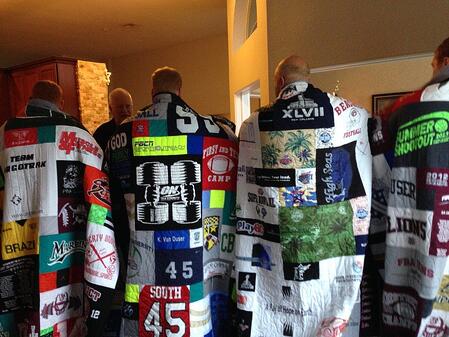 A group of 4 adult brothers wrapped in their T-shirt quilts as seen from the back.