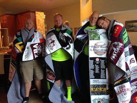 A group of 4 adult brothers wrapped in their T-shirt quilts as seen from the font.