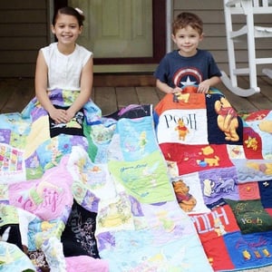 Two young kids hanging out with their T-shirt quilts on their front porch.