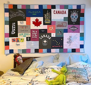 T-shirt Quilt hanging over bed made by Too Cool T-shirt Quilts